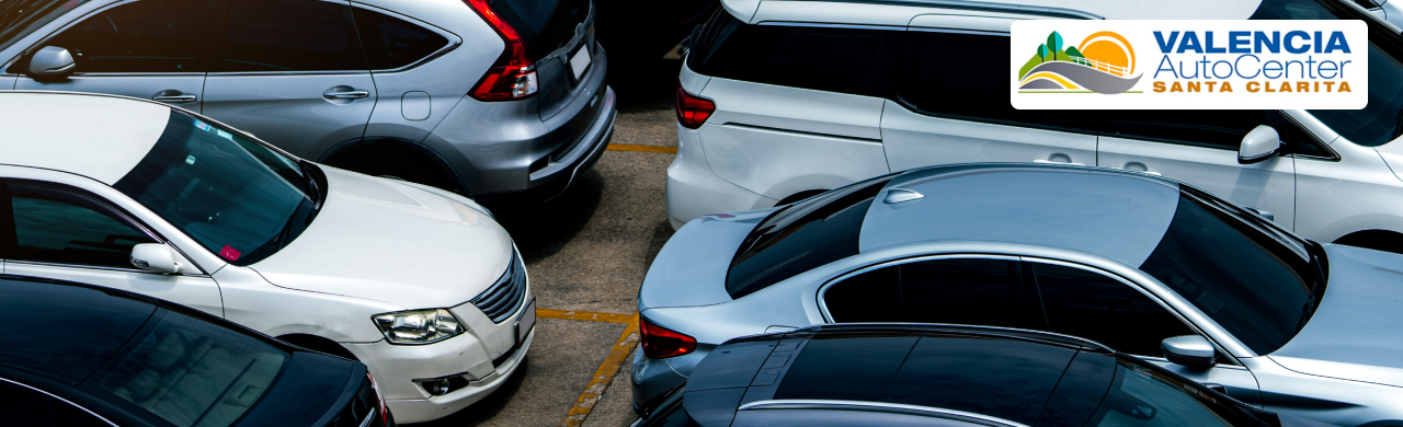 Photo of a spacious dealership lot at Valencia Auto Center with rows of new and used cars for sale under sunny skies