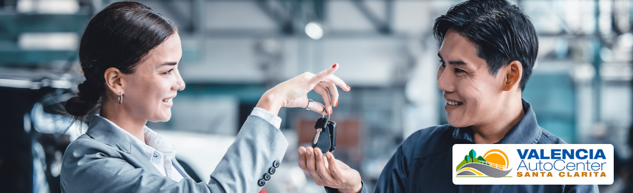 Sales consultant handing car keys to a happy buyer at a certified car dealership in Valencia