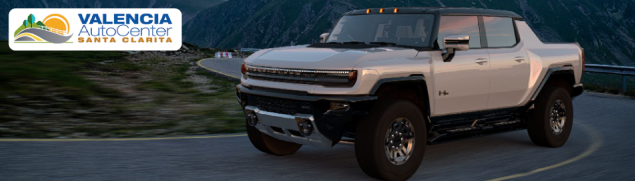 A GMC Acadia SUV with a sales consultant explaining financing options to a customer inside the Valencia Auto Center showroom.